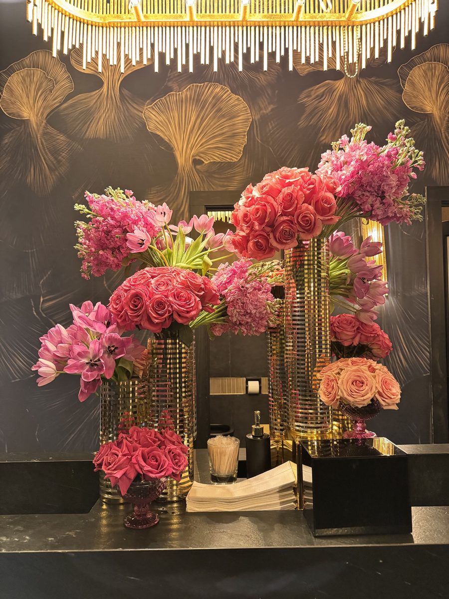 Tall pink floral arrangements on a mirrored console.